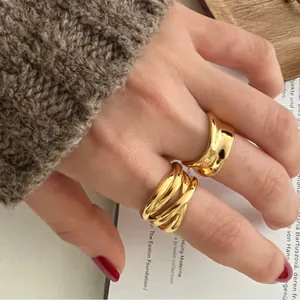 Detailed close-up of irregular high-gloss gold crisscross rings on a model's hand