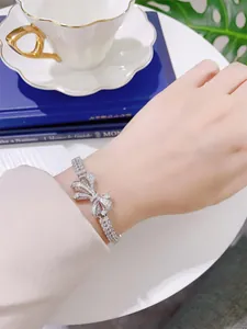 Elegant ribbon bow bracelet with sparkling simulated diamonds on wrist detail view.
