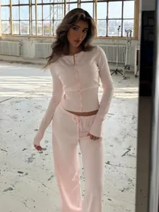 Dettaglio di un set cardigan rosa aderente in maglia e pantaloni larghi abbinati su modella