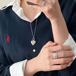 Detailed view of an irregular high-polish crisscross silver ring on a model's hand.