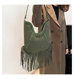 Detail of long tassels and silver studs on a green suede hobo bag carried by model.
