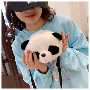 Close-up of a cute plush panda crossbody bag being held by a model wearing a blue sweater