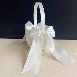 Elegant white satin flower girl basket with large ribbon bows for wedding ceremony