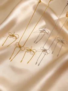 Detail of elegant stainless steel bow earrings and matching necklace set on silk.