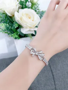 Elegant silver ribbon bow bracelet featuring sparkling pavé stones on a model wrist.