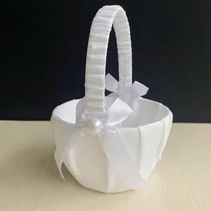 Detail of white satin wedding flower girl basket with elegant ribbon bow and pearl