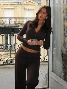 Donna indossa un elegante set cardigan in maglia marrone e pantaloni su un balcone.