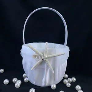 Detailed view of a white satin flower girl basket with starfish and pearls.