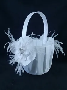 Detailed view of a white satin wedding flower girl basket with feather accents