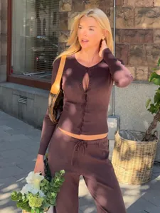 Donna alla moda che indossa un cardigan in maglia marrone slim e pantaloni coordinati