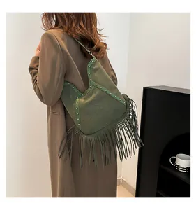 Bohemian green suede tassel shoulder bag with rivet details shown on a model's back.