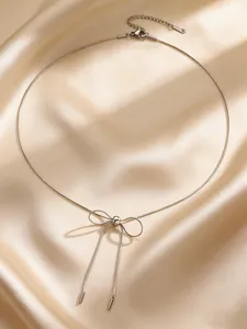 Elegant stainless steel bow necklace with snake chain detail on shiny satin background