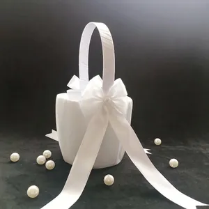 Close-up of elegant white satin flower girl basket with large bow for wedding ceremony