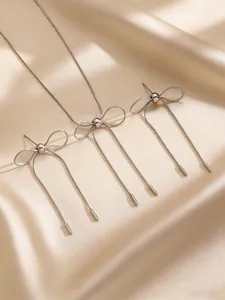 Elegant detail view of silver stainless steel bowknot necklace and earrings on silk