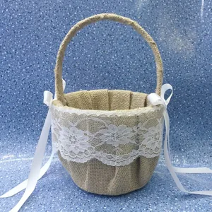 Rustic burlap flower girl basket with white lace and satin ribbons for wedding decor.