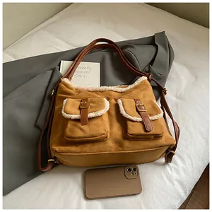 Detailed view of a brown suede plush shoulder bag featuring fur trim and buckles