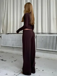 Vista posteriore di una donna che indossa un cardigan in maglia marrone e pantaloni larghi.