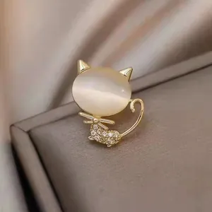 Close-up of elegant golden cat brooch with cat's eye stone and sparkly rhinestones.