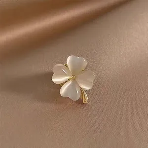 Detailed view of an elegant four-leaf clover brooch pin with white cat's eye stones