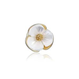 Detailed view of elegant white shell flower brooch with gold-tone center and reflection