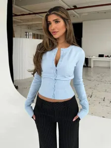 Scatto intero della modella con cardigan azzurro slim in un ambiente studio essenziale.