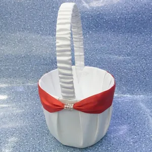 Detailed view of an elegant white satin wedding flower girl basket with a red bow