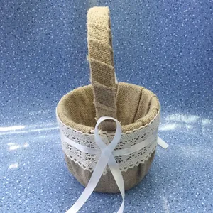 Close-up view of a burlap wedding flower girl basket with white lace trim and ribbon