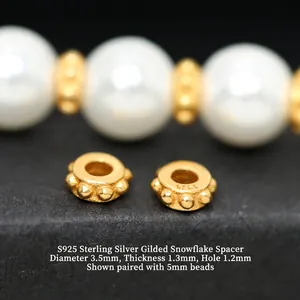 Macro detail of S925 gold-plated silver snowflake spacer beads for DIY jewelry.