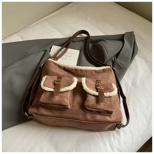 Detail view of brown suede shoulder bag with plush trim and front buckle pockets