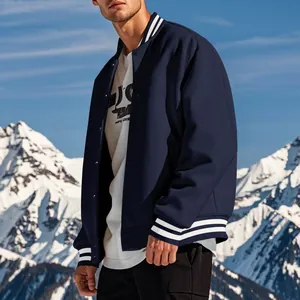 Dettaglio di una giacca varsity blu navy con polsini a righe su modello maschile.