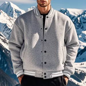 Dettaglio giacca varsity in pile grigio uomo con polsini a righe su montagne innevate