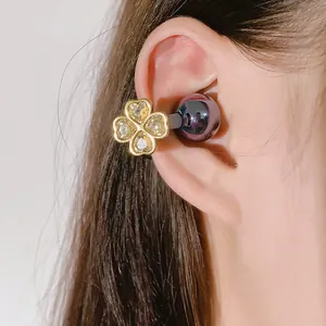 Close-up of a sparkling four-leaf clover diamond ear cuff for wireless earphones.