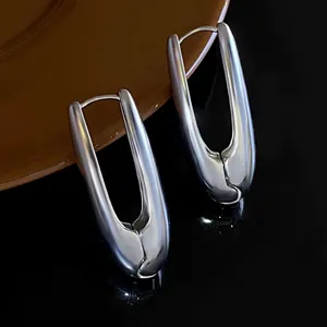 Close-up of silver-toned smooth U-shaped hoop earrings on a dark reflective surface