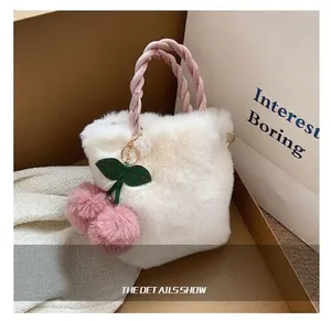 Nahaufnahme einer weißen Plüschtasche mit rosa geflochtenem Griff und Kirsch-Anhänger