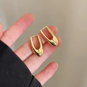 Detailed close-up of polished gold-plated elongated teardrop-shaped hoop earrings