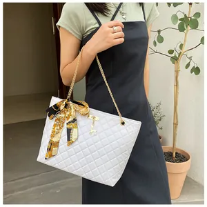Detailed view of an elegant white quilted tote bag with gold chain and silk scarf accent
