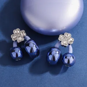 Close-up of blue four-leaf clover diamond earphone clips on a textured background
