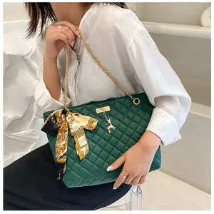 Green quilted shoulder bag with gold chain strap and decorative silk scarf on model