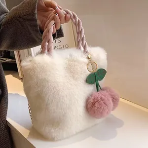 Nahaufnahme einer weichen weißen Plüschhandtasche mit süßem Kirsch-Pom-Pom-Anhänger