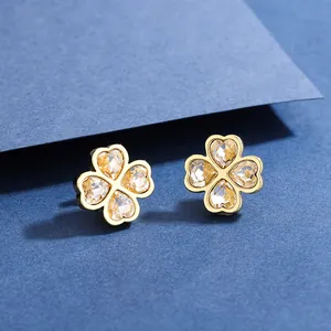 Detailed view of gold clover earrings with sparkling champagne crystals on blue background