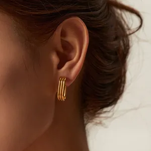 Close-up detail of stylish triple-layered U-shaped gold earrings worn on model's ear