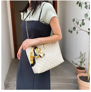 Elegant cream quilted shoulder bag featuring silk scarf decoration shown on a model