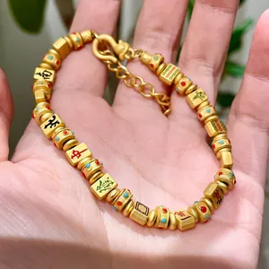 Detailansicht eines goldfarbenen Mahjong-Armband mit dreizehn Waisen-Charms in der Hand