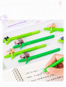 Close-up of green branch-shaped pen with cute monkey figure being used for writing.
