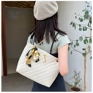 Stylish white quilted shoulder bag with silk scarf bow and gold chain strap detail.