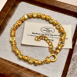Detailansicht eines goldfarbenen Mahjong-Armbands mit traditionellen Schriftzeichen