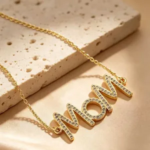 Vue macro détaillée d'un collier pendentif MOM doré avec un pavé de zircons brillants.