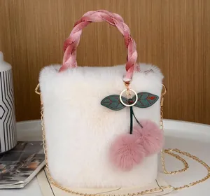 Detail der weißen flauschigen Handtasche mit rosa Kirsch-Pompon-Anhänger und Kette