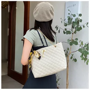 Detail view of a white quilted shoulder bag with silk scarf and gold chain strap.