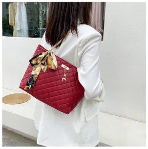 Elegant red quilted shoulder bag with chain strap and silk scarf bow on a model.